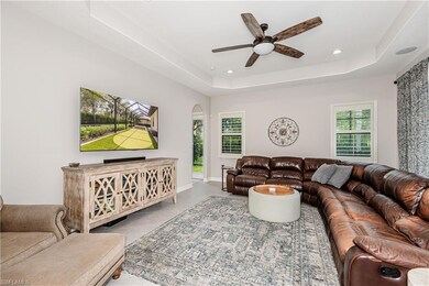 Living area with arched walkways, ceiling fan, a raised ceiling, recessed lighting, and tile patterned flooring