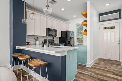Kitchen with black appliances, open shelves, a pe