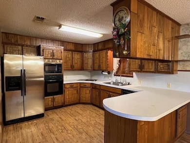 Kitchen featuring black appliances, a textured ceiling, kitchen peninsula, and sink