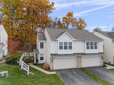 Traditional-style home featuring a shingled roof, asphalt driveway, a front yard, stone siding, and a garage
