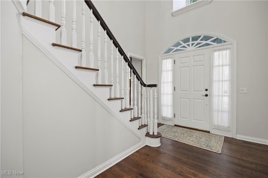 Foyer with wood finished floors, stairway, and a towering ceiling