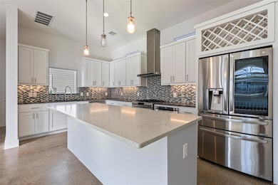 Kitchen featuring stainless steel appliances, a center island, white cabinets, concrete floors, and dark stone countertops