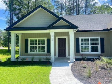 View of front of home featuring covered porch, a shingled roof, and a front yard