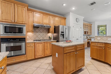 Recessed lighting, a built-in microwave over oven, and a stylish tile backsplash throughout.