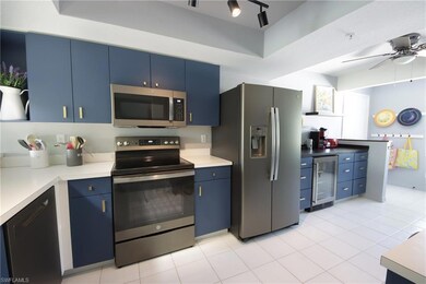 Kitchen featuring blue cabinets, ceiling fan, rail lighting, wine cooler, and appliances with stainless steel finishes