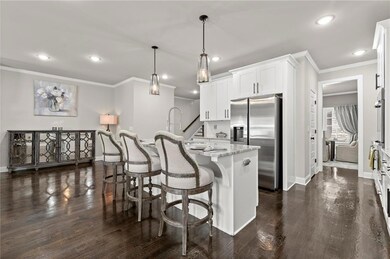 Kitchen with ornamental molding, appliances with stainless steel finishes, hanging light fixtures, a center island with sink, and a breakfast bar area