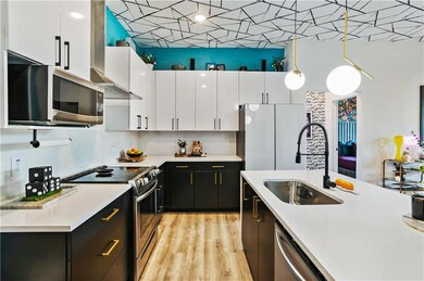 Kitchen featuring stainless steel appliances, a sink, white cabinetry, light countertops, and dark cabinetry