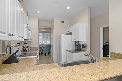 Kitchen featuring sink, white cabinets, white appliances, and light tile patterned floors