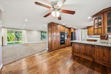 Kitchen featuring tasteful backsplash, brown cabinets, open floor plan, dark colored carpet, and recessed lighting