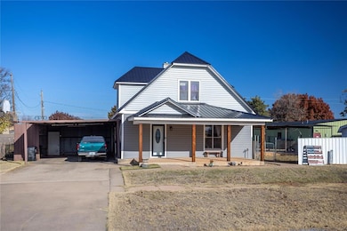 View of front of house with asphalt driveway, a porch, metal roof, and a carport