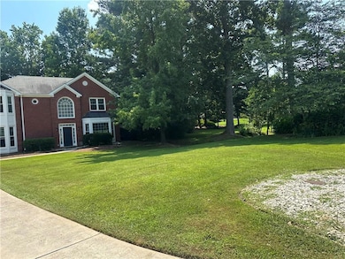 View of grassy yard featuring view of wooded area