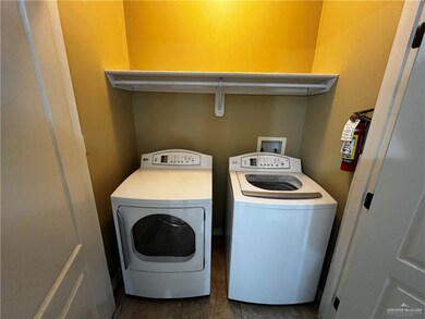 Laundry area with washing machine and clothes dryer and dark tile patterned flooring