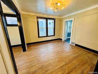 Spare room with wood finished floors, a chandelier, and ornamental molding