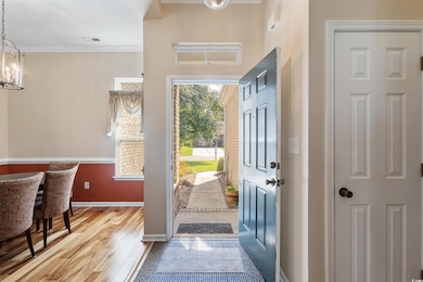 Foyer entrance with crown molding, light wood-style flooring, a chandelier, and a textured ceiling