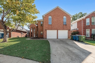 Traditional home featuring a front yard, concrete driveway, brick siding, and a garage