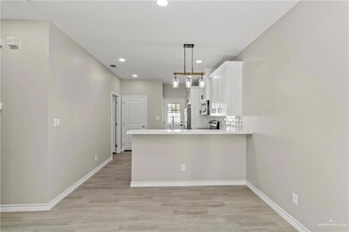 Kitchen featuring hanging light fixtures, white cabinetry, stove, and kitchen peninsula