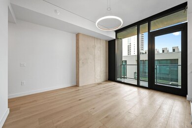 Empty room with floor to ceiling windows, light wood-type flooring, and a city view