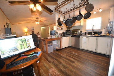 Kitchen featuring a textured ceiling, white cabinets, dark wood-style flooring, dark countertops, and dishwasher
