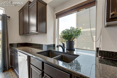 Kitchen with dark brown cabinets, a healthy amount of sunlight, stainless steel dishwasher, and a sink