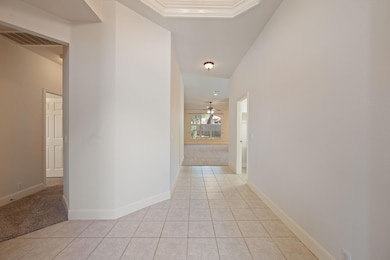 Hallway with light tile patterned flooring, light carpet, and ornamental molding