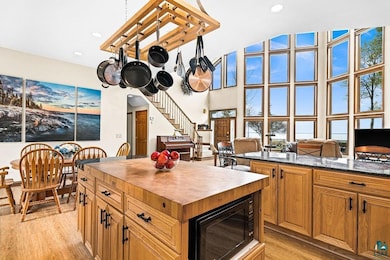 Kitchen with black microwave, butcher block counters, light wood-style flooring, a kitchen island, and recessed lighting