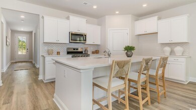 Kitchen featuring stainless steel appliances, tasteful backsplash, a center island with sink, light wood finished floors, and recessed lighting