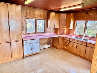 Kitchen with wooden walls, a sink, a baseboard heating unit, light countertops, and light floors