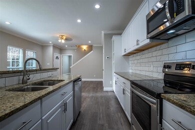 Kitchen with dark hardwood / wood-style floors, sink, white cabinets, backsplash, and stainless steel appliances