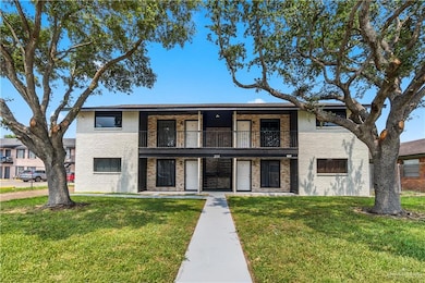Townhome / multi-family property featuring brick siding, a front lawn, and a balcony