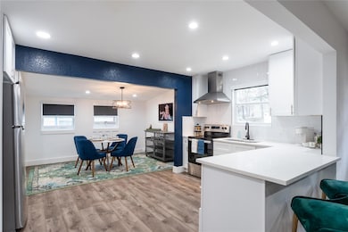 Kitchen with backsplash, plenty of natural light, appliances with stainless steel finishes, wall chimney exhaust hood, and recessed lighting