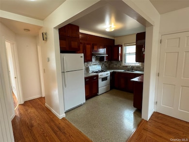 Kitchen featuring tasteful backsplash, white appliances, under cabinet range hood, and light wood-style floors