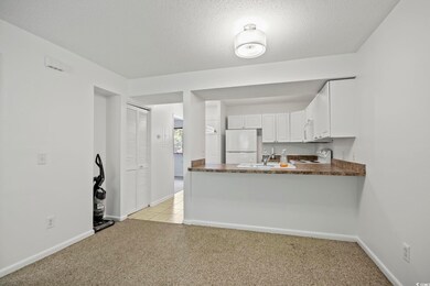 Kitchen with a textured ceiling, white cabinetry, 