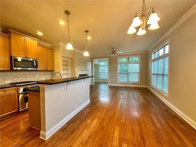 Kitchen with appliances with stainless steel finishes, ornamental molding, dark countertops, tasteful backsplash, and dark wood-style flooring