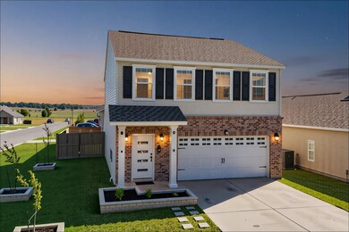 Traditional-style house featuring brick siding, a shingled roof, concrete driveway, and an attached garage