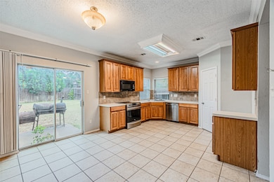 Kitchen with light countertops, backsplash, crown molding, a textured ceiling, and light tile patterned floors