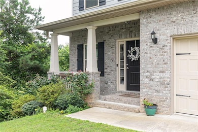 Entrance to property featuring a porch, brick siding, and a garage