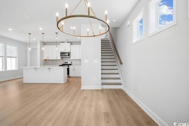 Unfurnished living room featuring light wood-style flooring, recessed lighting, a chandelier, and stairs
