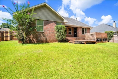 Rear view of property with a fenced backyard, brick siding, and a deck
