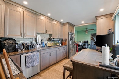 Kitchen featuring dark stone countertops, appliances with stainless steel finishes, light wood-type flooring, recessed lighting, and a ceiling fan