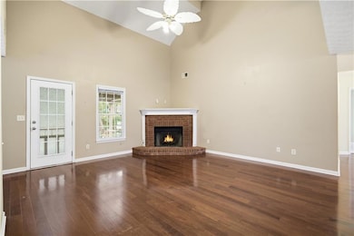 Unfurnished living room with high vaulted ceiling, dark wood finished floors, a fireplace, and ceiling fan