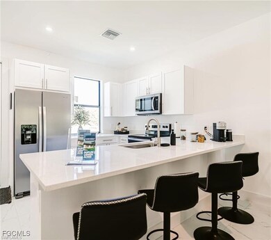 Kitchen with a breakfast bar, a peninsula, white cabinetry, and recessed lighting