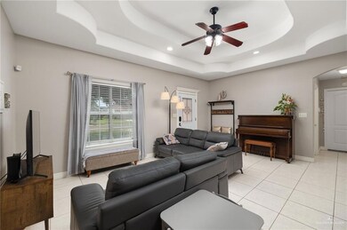 Tiled living room featuring ceiling fan and a raised ceiling