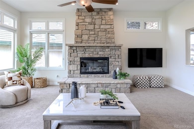 Sunlight cascades across the stone fireplace and flagstone hearth, each surface aglow with warmth and artistry.