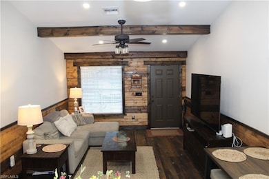 Living area with visible vents, wooden walls, beam