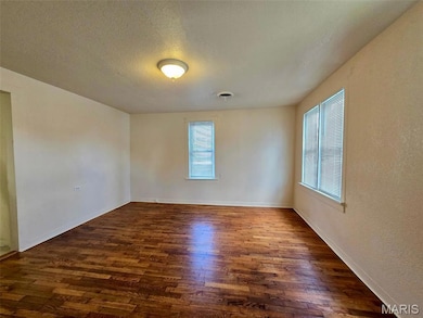 Spare room with a textured ceiling and dark wood-style flooring