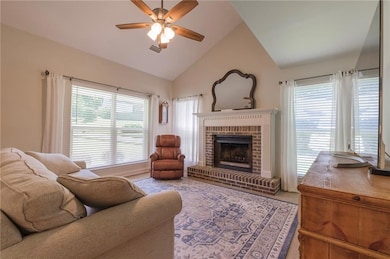 Living area with ceiling fan, a brick fireplace, and high vaulted ceiling