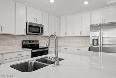 Kitchen featuring decorative backsplash, white cabinets, and stainless steel appliances