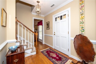 Foyer with lovely wood floor, crown molding and chair rail.