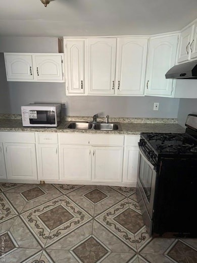 Kitchen featuring range, white cabinets, and ventilation hood