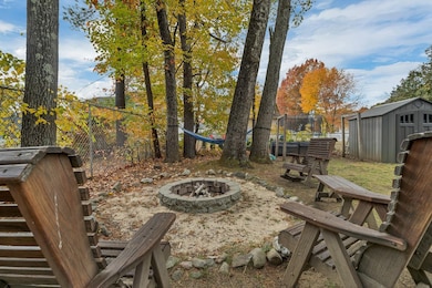spacious backyard with an outdoor firepit, ample greenspace, and mature trees.